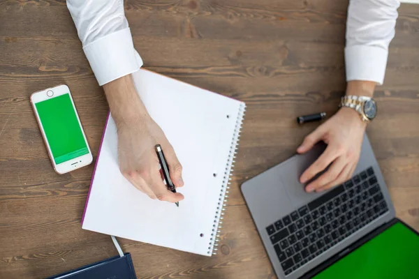 Bilgisayarı, tableti ve telefonu olan bir ofis masası. Erkeklerin elleri akıllı telefon tutuyor. Ofis İşçi Masası