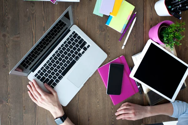 Bilgisayarı, tableti ve telefonu olan bir ofis masası. Dişi eller kalemi tutar. Ofis İşçi Masası