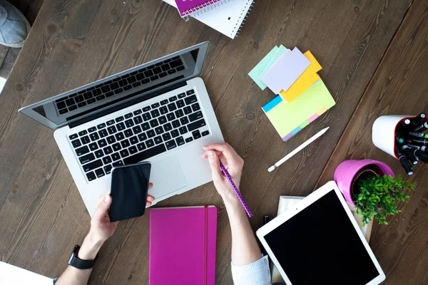 Bilgisayarı, tableti ve telefonu olan bir ofis masası. Dişi eller kalemi tutar. Ofis İşçi Masası