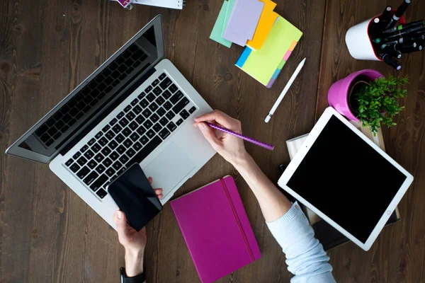            Bilgisayarı, tableti ve telefonu olan bir ofis masası. Dişi eller kalemi tutar. Ofis İşçi Masası