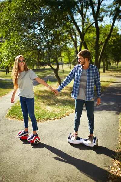 Młody mężczyzna i kobieta jazda na Hoverboard w parku. Deskorolka Smart — Zdjęcie stockowe