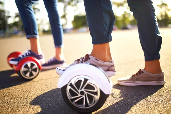 Młody mężczyzna i kobieta jazda na Hoverboard w parku. Deskorolka Smart — Zdjęcie stockowe