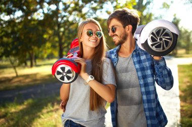 young man and woman riding on the Hoverboard in the park. content technologies. a new movement clipart