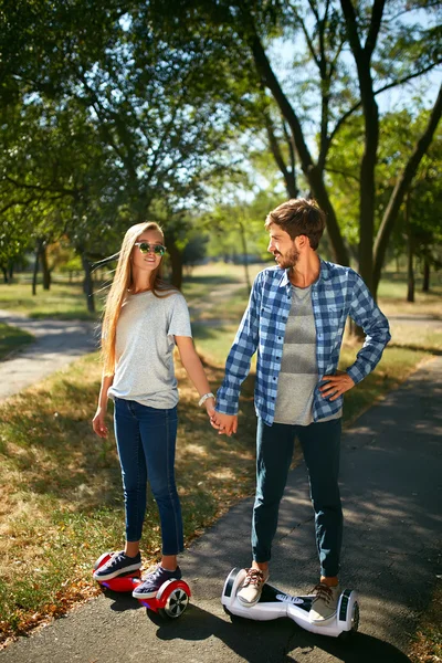 Jonge man en vrouw op de Hoverboard in het park rijden. inhoud technologieën. een nieuwe beweging — Stockfoto