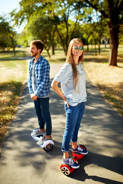 Fiatal férfi és nő, lovaglás a Hoverboard a parkban. tartalom technológiák. egy új mozgalom — Stock Fotó