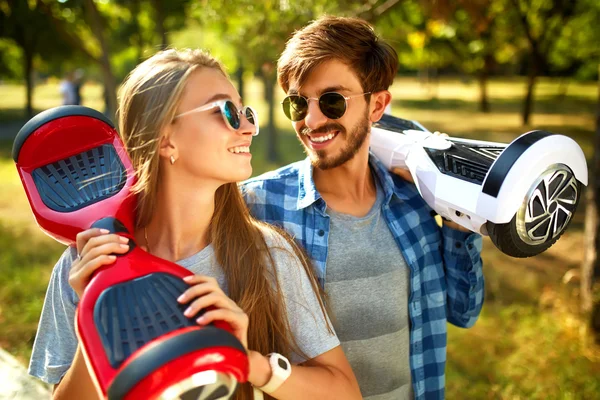 Young man and woman riding on the Hoverboard in the park. content technologies. a new movement — Stock Photo, Image