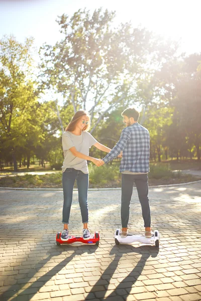 Jeune homme et jeune femme chevauchant le Hoverboard dans le parc. technologies de contenu. un nouveau mouvement — Photo