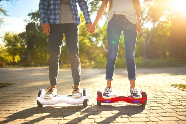 Jeune homme et jeune femme chevauchant le Hoverboard dans le parc. technologies de contenu. un nouveau mouvement — Photo