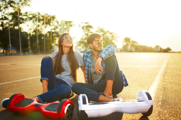 Jovem homem e mulher montando no Hoverboard no parque. tecnologias de conteúdo. um novo movimento — Fotografia de Stock