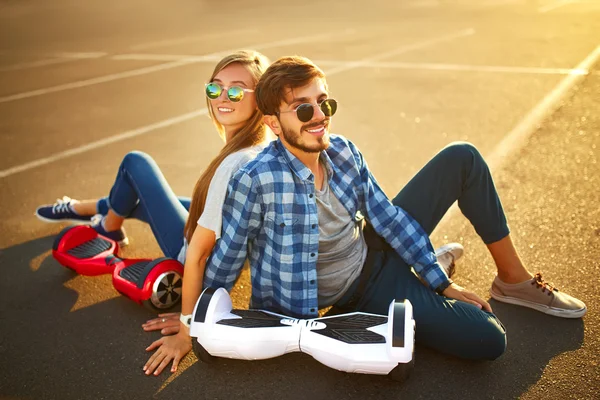 Jovem homem e mulher montando no Hoverboard no parque. tecnologias de conteúdo. um novo movimento — Fotografia de Stock