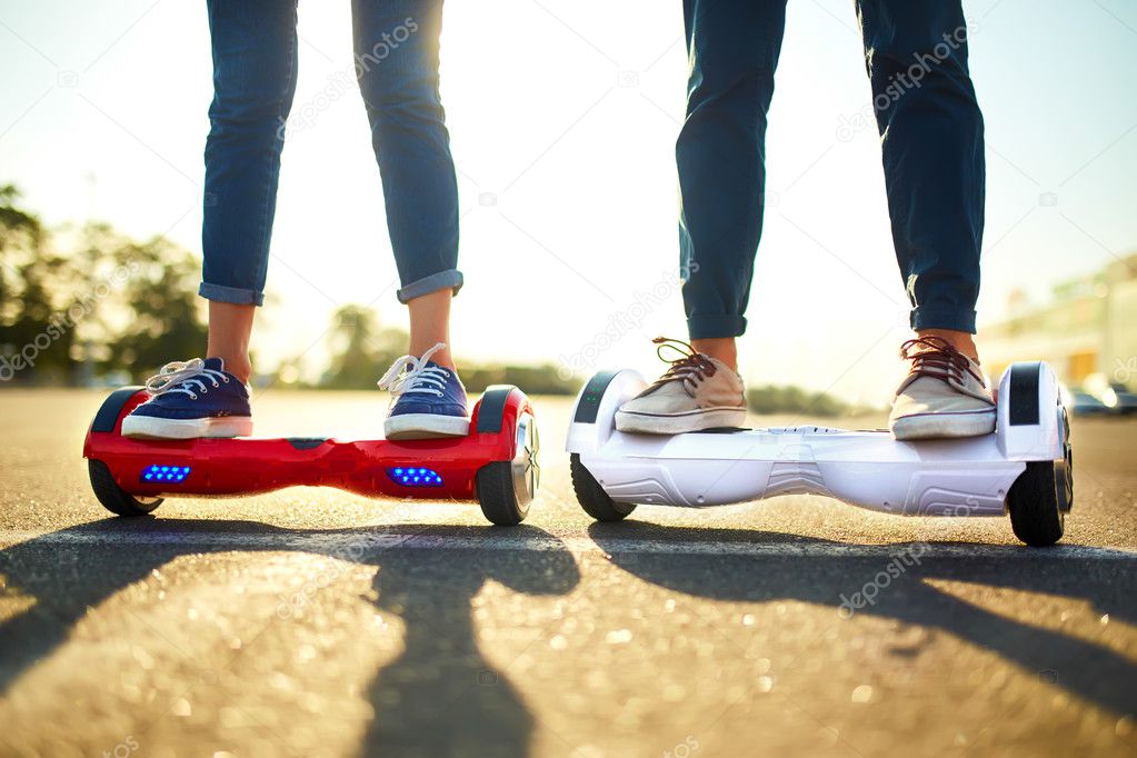 young man and woman riding on the Hoverboard in the park. content technologies. a new movement