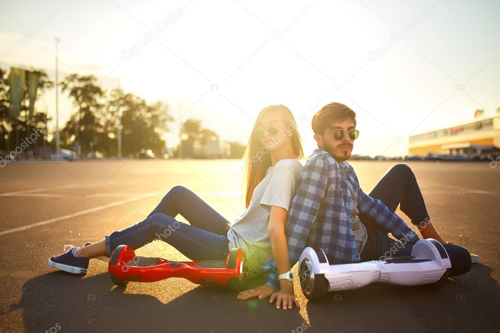 young man and woman riding on the Hoverboard in the park. content technologies. a new movement