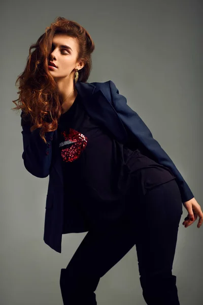 Menina bonita vestindo uma jaqueta, camisa e calças posando em um fundo cinza. foto do estúdio . — Fotografia de Stock