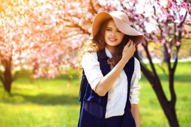 Genç güzel Moda Bayan çiçekli ağacın yanında poz açık portresi. Modeli şık Aksesuar ve kıyafet giyiyor. . Kadın güzellik ve moda.