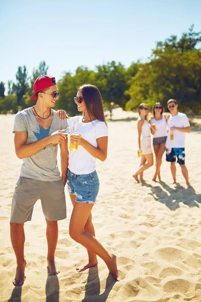 Grupo de amigos pasando el rato con cerveza en la playa. Excelente clima soleado. Hermosas figuras.Concepto de verano — Foto de Stock