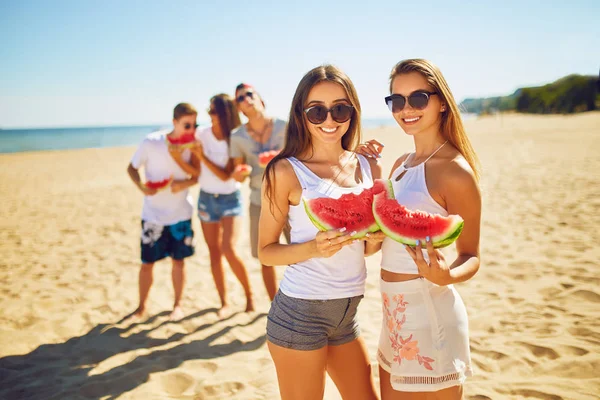Group of friends having fun eating watermelon. on the beach. Excellent sunny weather. . Super mood. Summer concept