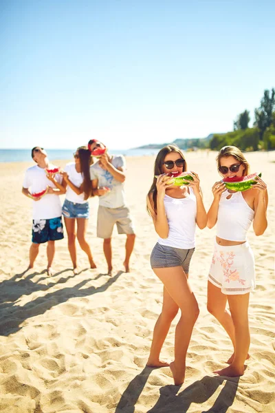 Grupo de amigos divirtiéndose comiendo sandía. en la playa. Excelente clima soleado. .. Super estado de ánimo. Concepto de verano — Foto de Stock