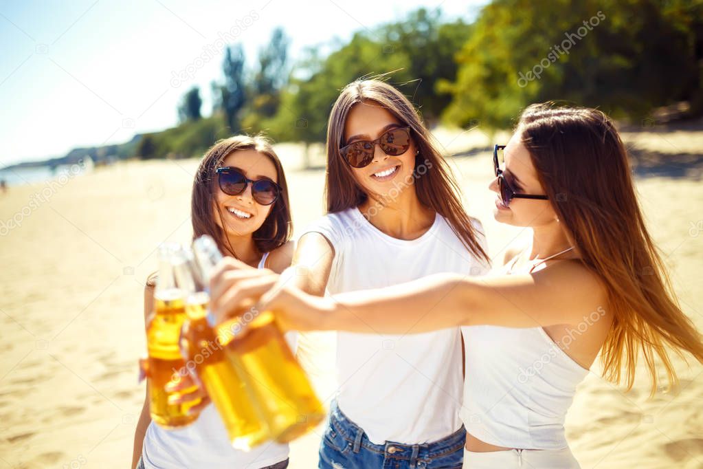 Group of friends hanging out with beer at the beach.  Excellent sunny weather. Beautiful figures.Summer concept