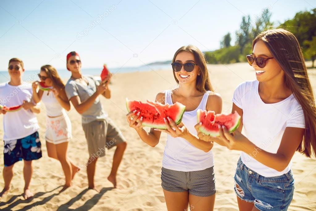 Group of friends having fun eating watermelon. on the beach. Excellent sunny weather. . Super mood. Summer concept