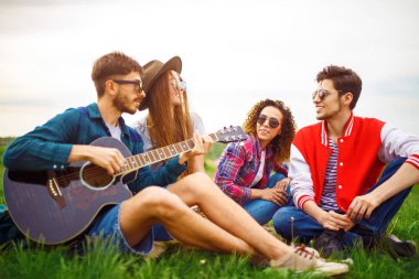 Grup arkadaşıyla birlikte eğleniyor. Adam gitar çalıyor. Herkes büyük bir ruh var.