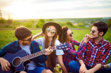 Grup arkadaşıyla birlikte eğleniyor. Adam gitar çalıyor. Herkes büyük bir ruh var.