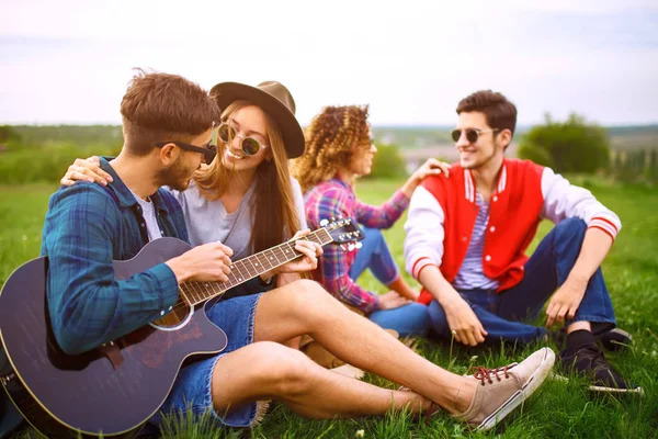 Група друзів насолоджується вечіркою. Хлопець грає на гітарі. У кожного чудовий настрій . — стокове фото