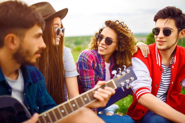 Grup arkadaşıyla birlikte eğleniyor. Adam gitar çalıyor. Herkes büyük bir ruh var.