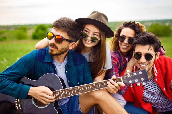 Grup arkadaşıyla birlikte eğleniyor. Adam gitar çalıyor. Herkes büyük bir ruh var.