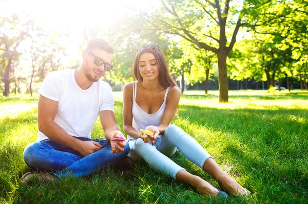 Jeune fille et garçon jouant avec un fidget spinners dans le parc. jouet anti-stress. Journée ensoleillée d'été. Ils rient et sourient — Photo