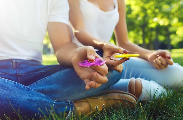 Młoda dziewczyna i chłopak gra z fidget błystki w parku. Zabawka łagodzi stres. Słoneczny letni dzień. Śmiech i uśmiech — Zdjęcie stockowe