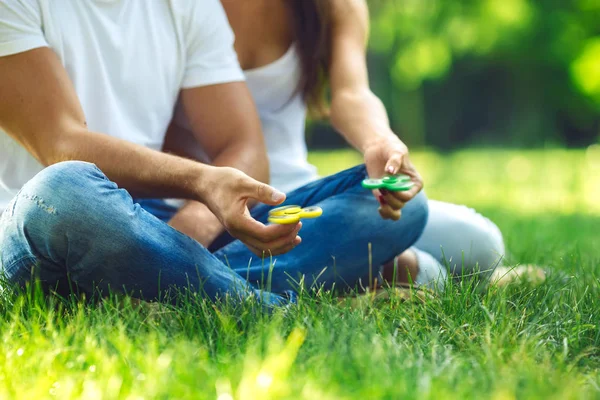 Jeune fille et garçon jouant avec un fidget spinners dans le parc. jouet anti-stress. Journée ensoleillée d'été. Ils rient et sourient — Photo