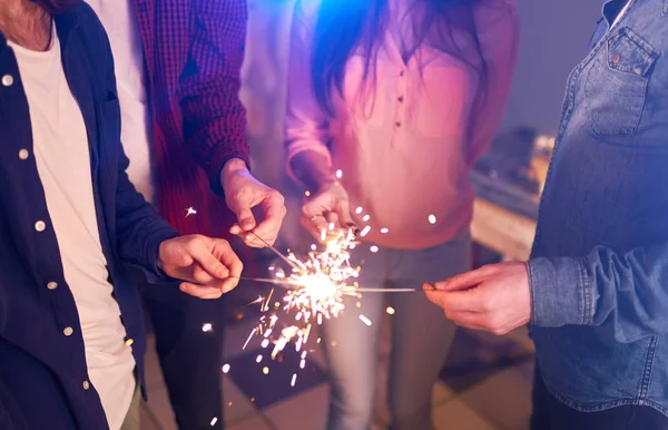 Group of friends having fun with sparklers. young people laugh. celebrating New Year together. Group of beautiful young people in Santa hats. Blur Background