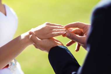Çift holding düğün günbatımı arka plan üzerinde eller. O bir alyans koyar
