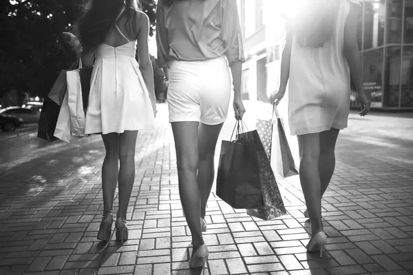 Beautiful girl with packages after shopping A picture of a group of happy friends shopping in the city. Girl walking around the city after shopping. good mood. black and white photo