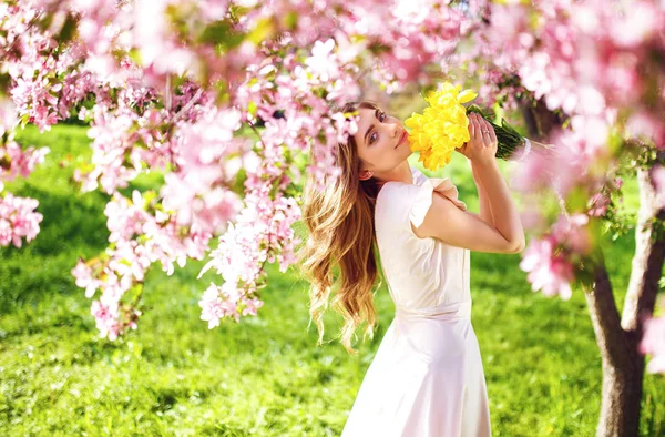 Spring Style. Beautiful Young Brunette Woman In Nice Spring Dress With A Bouquet Of Tulips. Beautiful Spring Garden. Fashion Spring Summer Photo