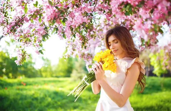 Spring Style. Beautiful Young Brunette Woman In Nice Spring Dress With A Bouquet Of Tulips. Beautiful Spring Garden. Fashion Spring Summer Photo