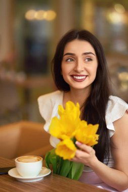 Bahar Lale çiçek buketi Cafe olan güzel kadın. Kahve içme ve telefon kullanarak kadın. Bahar tarzı. Esmer kadın güzel Spring.Beautiful bahar havasında. Moda ilkbahar/yaz.