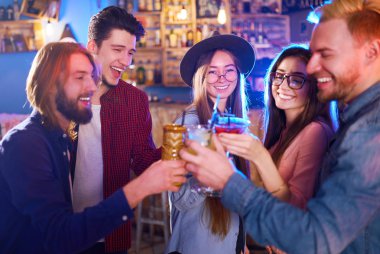 Genç grup arkadaşıyla birlikte bir gece kulübünde parti ve içecekler kızartma. Mutlu gençlerle barda kokteyller. İnsanlar büyük bir ruh var ve onlar çok gülümseme.