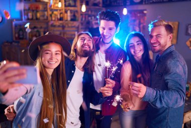 Genç grup arkadaşıyla birlikte bir gece kulübünde parti ve içecekler kızartma. Mutlu gençlerle maytap barda. İnsanlar büyük bir ruh var ve onlar çok gülümseme.