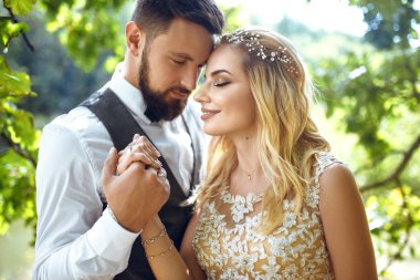 Düğün günü parkta poz mutlu yeni evliler şık birkaç. Mükemmel bir çift gelin, damat poz ve öpüşme 