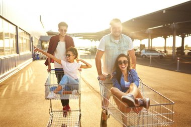 Grup alışveriş arabaları üzerinde eğleniyor mutlu genç insan. Alışveriş sepeti yarış çok ırklı çocuklar. Güzel yaz günü güneş ışığı ile. Yaşam tarzı kavramı. Arkadaş grubu zevk yaşam. 