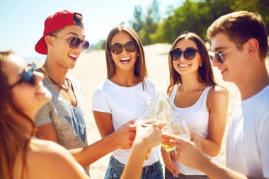 Grup arkadaşıyla sahilde bira dışarı asılı. Mükemmel güneşli havalarda. Güzel resimler. Süper ruh hali. Yaz konsepti.