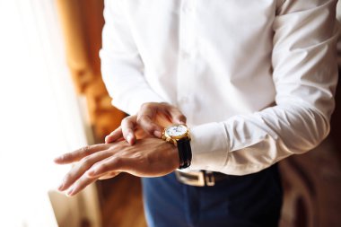 Erkek kol saati, adam saate bakıyor. İş adamı saati, iş adamı kol saatini kontrol ediyor. Damadın elleri, kol saatini ayarlayan, düğün hazırlıkları, damat aksesuarları..