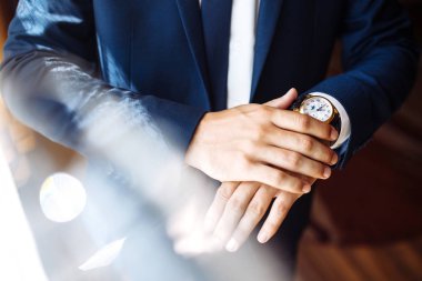 Erkek kol saati, adam saate bakıyor. İş adamı saati, iş adamı kol saatini kontrol ediyor. Damadın elleri, kol saatini ayarlayan, düğün hazırlıkları, damat aksesuarları..