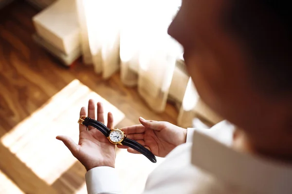 Men\'s wrist watch, the man is watching the time. Businessman clock, businessman checking time on his wristwatch. Groom\'s hands in a suit adjusting wristwatch, wedding preparations, groom accessories.