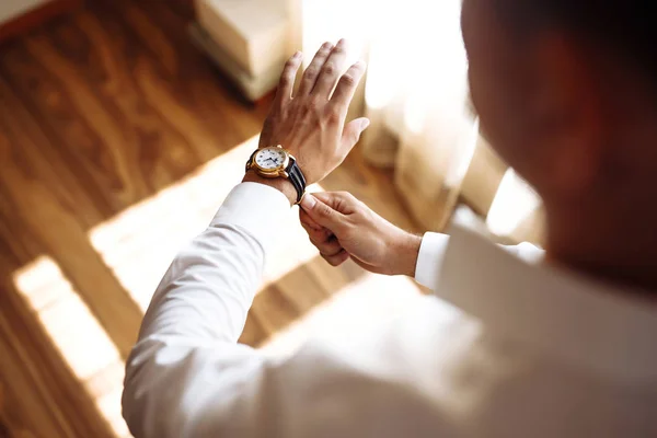 Men\'s wrist watch, the man is watching the time. Businessman clock, businessman checking time on his wristwatch. Groom\'s hands in a suit adjusting wristwatch, wedding preparations, groom accessories.