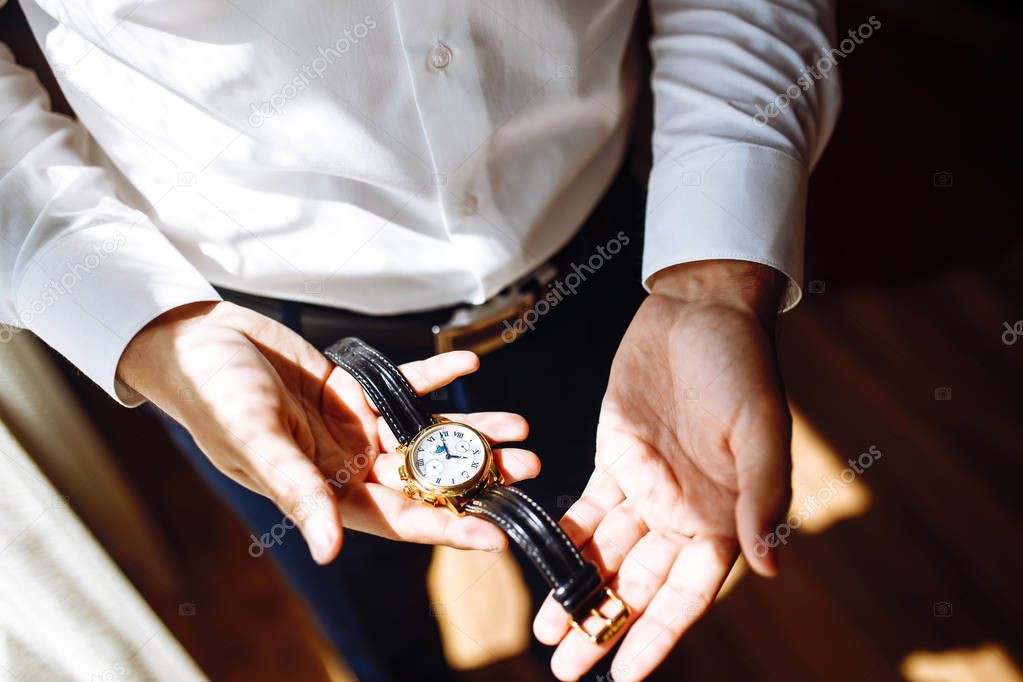 Men's wrist watch, the man is watching the time. Businessman clock, businessman checking time on his wristwatch. Groom's hands in a suit adjusting wristwatch, wedding preparations, groom accessories.