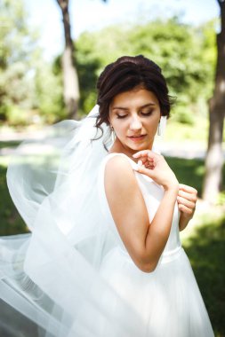 Parkta yürüyüş için bir buketi olan güzel bir gelin. Beyaz elbiseli genç gelin. Profesyonel makyajlı ve saç stili olan güzel bir kadın. Güzel bir gelin portresi. Düğün günü. Evlilik..