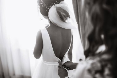 Gelinin sabahı. Beyaz elbiseli, elinde düğün buketi olan güzel, gülümseyen esmer gelin. Profesyonel makyajlı ve saç stili olan zarif bir kadın. Gelinin düğün sabahı. 