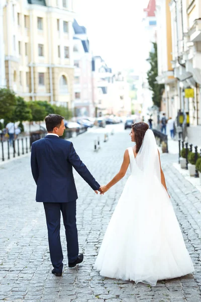 华丽的婚礼夫妇走在城市里 这对新婚夫妇穿着时髦的西服 穿着漂亮的白色礼服 在城市的街道上散步 在一起 结婚的概念 — 图库照片